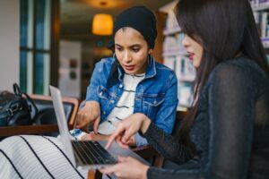 Two women working around a laptop